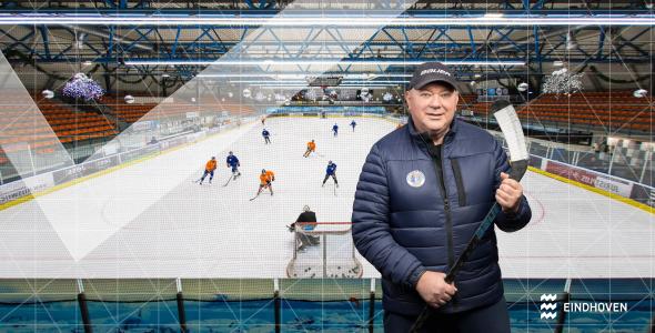 IJhockeytrainer die voor een ijshockeyveld staat