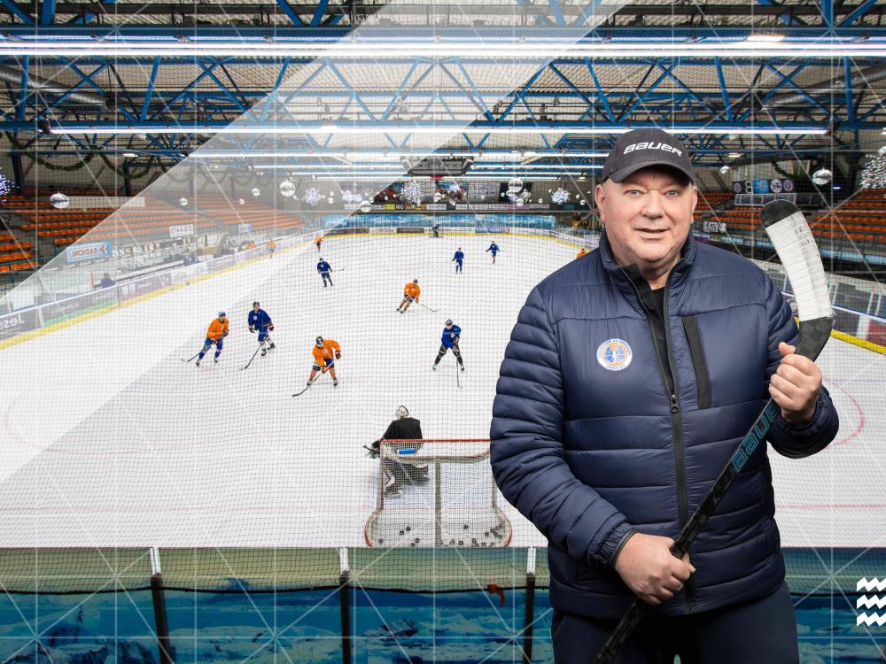 IJhockeytrainer die voor een ijshockeyveld staat